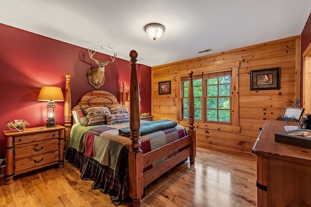 bedroom with wooden walls and light wood finished floors