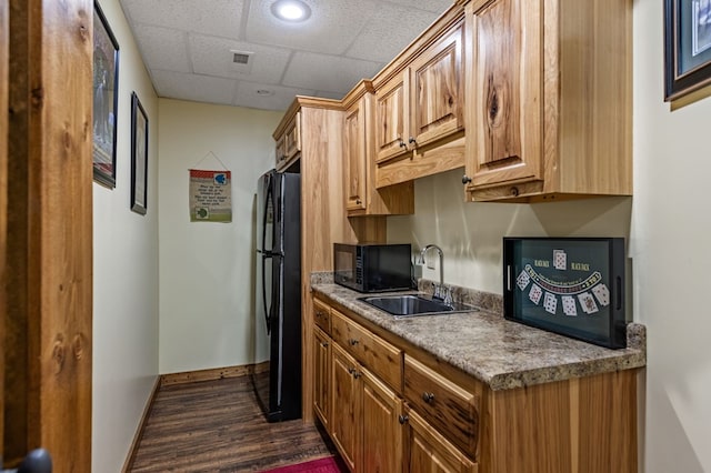 kitchen with black appliances, a sink, dark wood-type flooring, baseboards, and a paneled ceiling