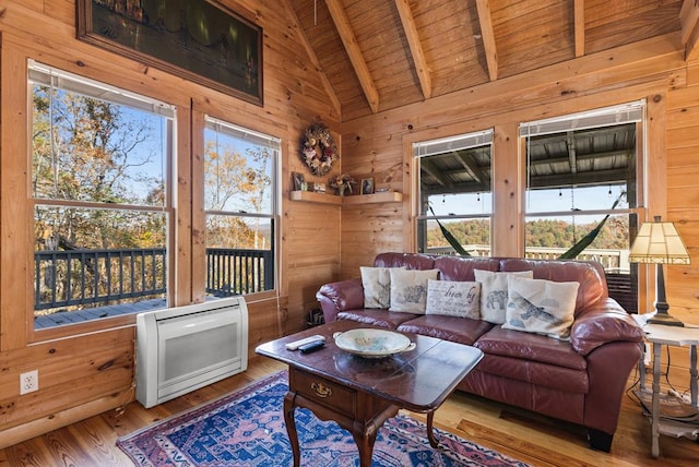 living room with heating unit, wood walls, wood ceiling, hardwood / wood-style flooring, and beam ceiling