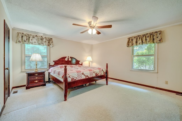 carpeted bedroom with a textured ceiling, visible vents, crown molding, a ceiling fan, and baseboards