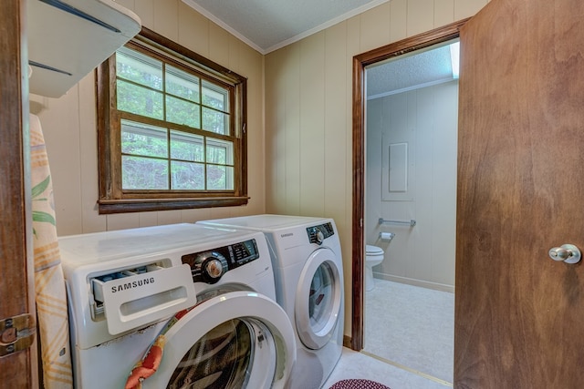 laundry area featuring crown molding, wood walls, laundry area, and separate washer and dryer