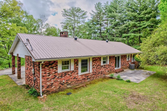 back of property with a chimney, a patio area, central AC unit, and a lawn