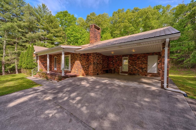 view of front facade featuring concrete driveway, brick siding, a chimney, and a front yard