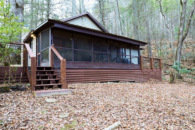 view of home's exterior featuring a sunroom, stairway, and a wooded view