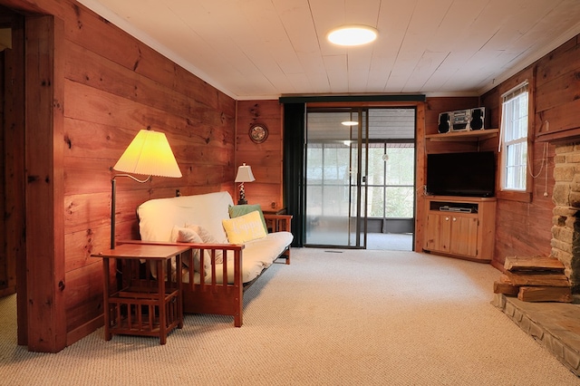 sitting room with ornamental molding, carpet, wood ceiling, and wood walls