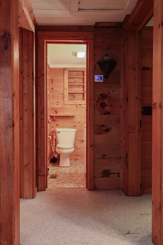 hall with carpet floors and wood walls