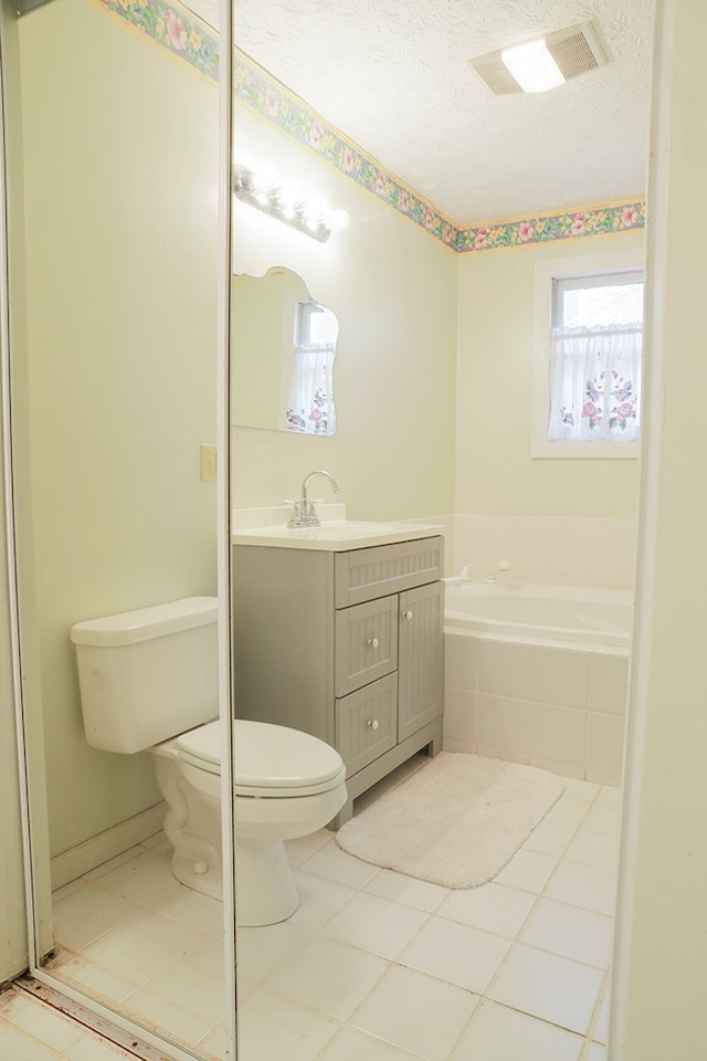 full bathroom with a textured ceiling, toilet, vanity, a bath, and tile patterned floors