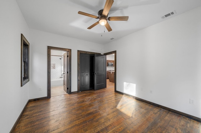 unfurnished bedroom featuring ceiling fan, dark hardwood / wood-style flooring, and connected bathroom