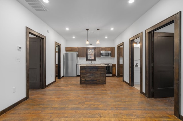 kitchen featuring a center island, stainless steel appliances, dark wood-type flooring, tasteful backsplash, and pendant lighting