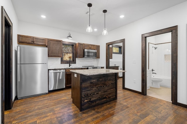 kitchen featuring sink, a center island, dark hardwood / wood-style floors, decorative light fixtures, and appliances with stainless steel finishes