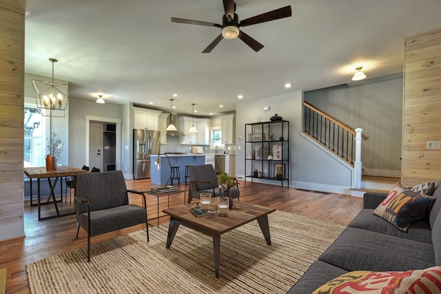 living room featuring ceiling fan with notable chandelier, a healthy amount of sunlight, and light hardwood / wood-style flooring