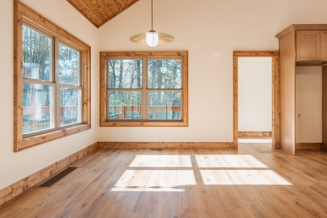 unfurnished dining area featuring visible vents, lofted ceiling, baseboards, and light wood-style flooring