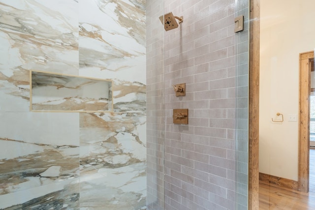 full bathroom with tiled shower and wood finished floors