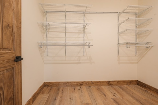 walk in closet with wood finished floors