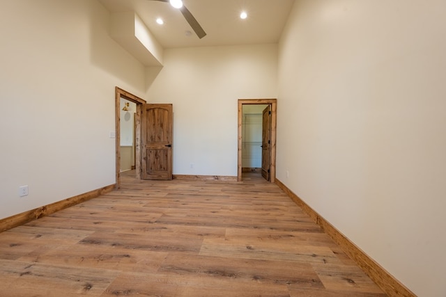 spare room with baseboards, a high ceiling, recessed lighting, ceiling fan, and light wood-type flooring