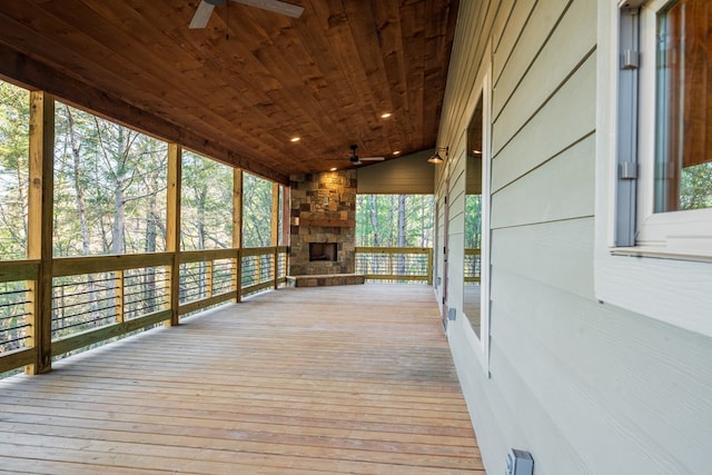 wooden deck featuring an outdoor stone fireplace and a ceiling fan