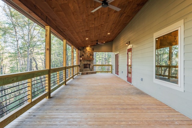 deck featuring an outdoor stone fireplace and ceiling fan