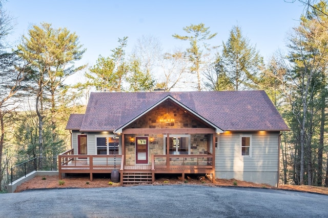 rustic home featuring stone siding and roof with shingles