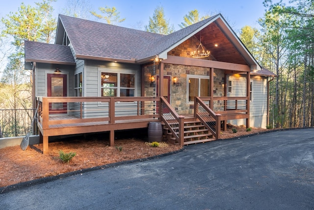 rustic home with stone siding and a shingled roof