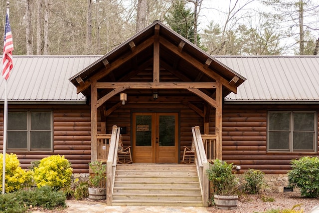 view of exterior entry featuring crawl space, french doors, metal roof, and faux log siding