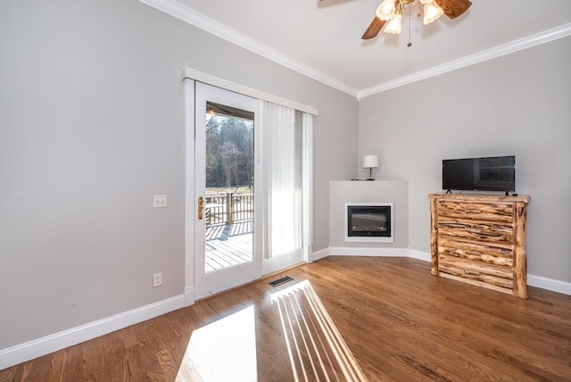 33 Tj Mote Rd, Dahlonega, GA 30533 - unfurnished living room featuring crown molding, baseboards, wood finished floors, a ceiling fan, and a glass covered fireplace