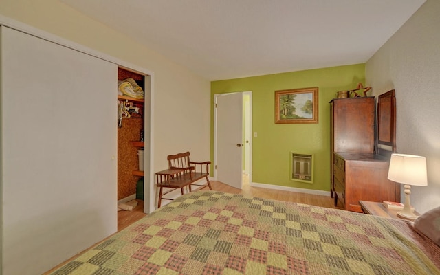 bedroom featuring heating unit, light hardwood / wood-style floors, and a closet