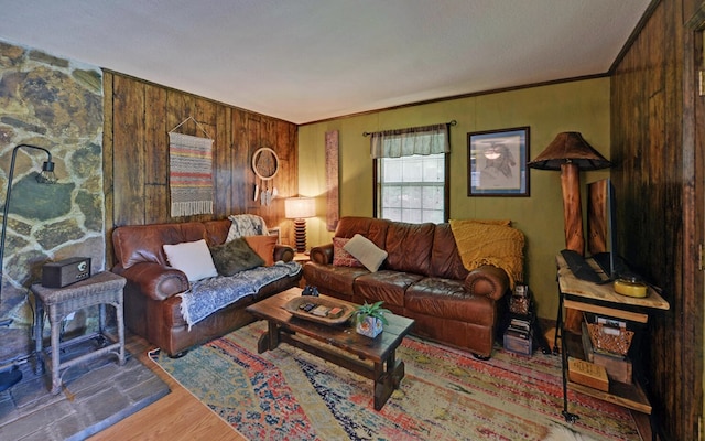 living room with wood-type flooring, ornamental molding, and wood walls