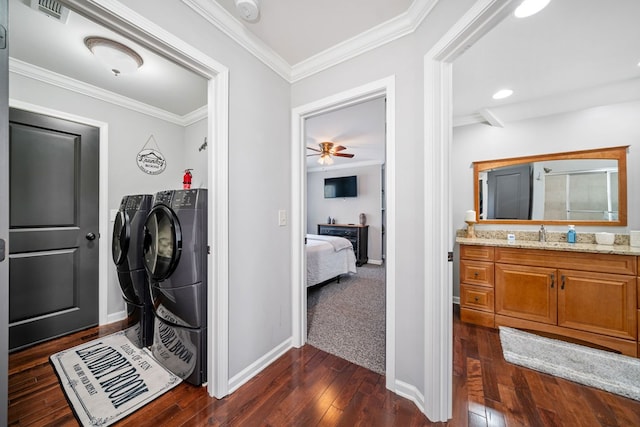 laundry area with ornamental molding, ceiling fan, dark wood-type flooring, sink, and washing machine and dryer