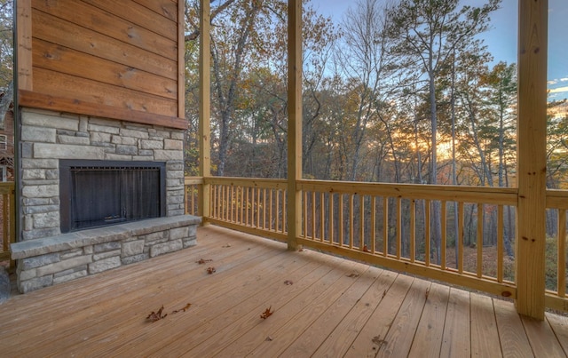 deck at dusk featuring an outdoor stone fireplace