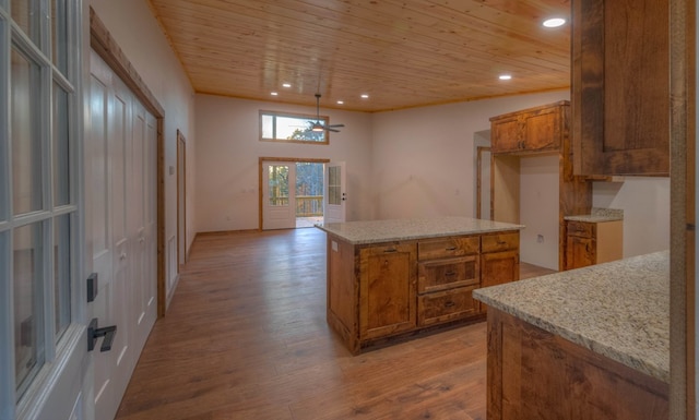 kitchen with light stone countertops, ceiling fan, wood ceiling, light hardwood / wood-style flooring, and a kitchen island