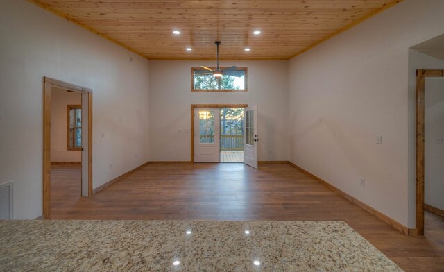 unfurnished dining area with a towering ceiling, light hardwood / wood-style floors, and wooden ceiling