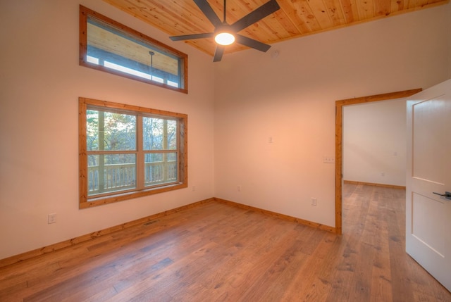 unfurnished room with ceiling fan, wood ceiling, light hardwood / wood-style floors, and a towering ceiling