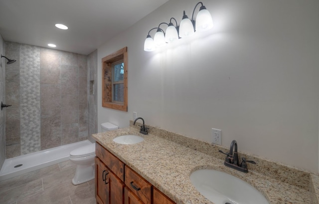 bathroom featuring a tile shower, vanity, tile patterned floors, and toilet