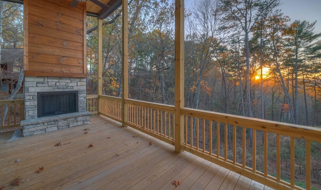 deck at dusk with an outdoor stone fireplace