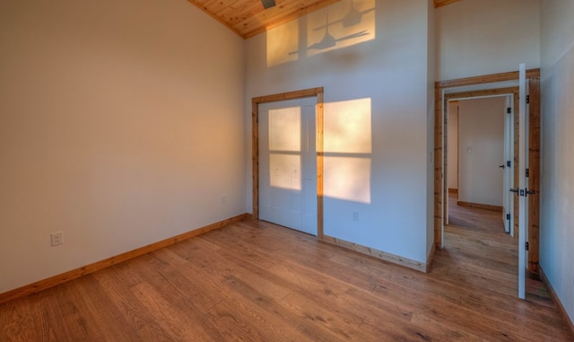 empty room featuring wooden ceiling, light hardwood / wood-style flooring, and high vaulted ceiling