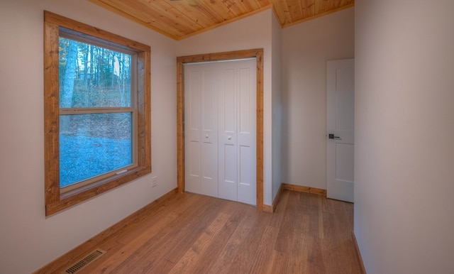 unfurnished bedroom with light hardwood / wood-style flooring, lofted ceiling, wood ceiling, and a closet