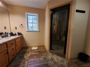 bathroom featuring a shower with door and vanity