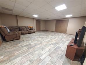 living room featuring light hardwood / wood-style flooring and a paneled ceiling