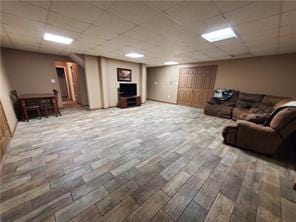 unfurnished living room with wood-type flooring and a drop ceiling