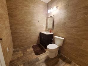 bathroom with vanity, toilet, and tile walls