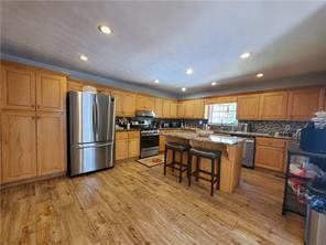 kitchen with backsplash, appliances with stainless steel finishes, a kitchen breakfast bar, a kitchen island, and light hardwood / wood-style floors