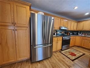 kitchen featuring appliances with stainless steel finishes, exhaust hood, and light hardwood / wood-style floors