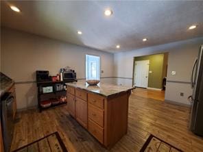 kitchen with dark wood-type flooring, a kitchen island, and stainless steel fridge