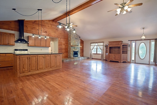 kitchen featuring decorative light fixtures, light hardwood / wood-style floors, wooden walls, and wall chimney range hood