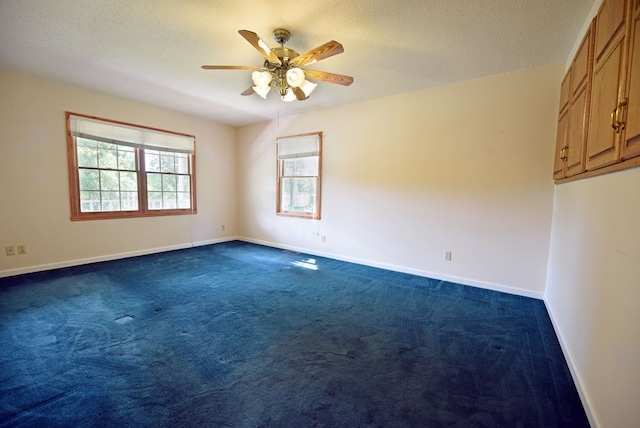 unfurnished room featuring ceiling fan, dark carpet, and a textured ceiling