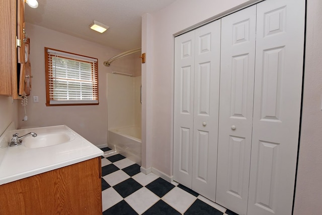 bathroom featuring a textured ceiling, vanity, and  shower combination