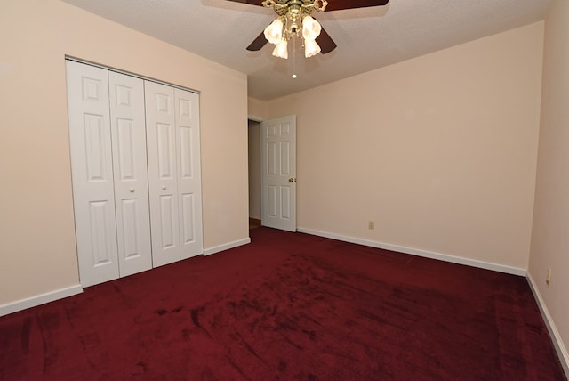 unfurnished bedroom with ceiling fan, dark carpet, a textured ceiling, and a closet