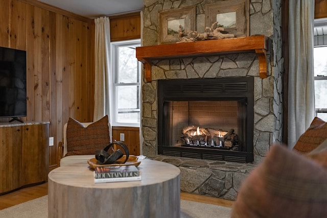 sitting room with wooden walls, a fireplace, light hardwood / wood-style floors, and ornamental molding