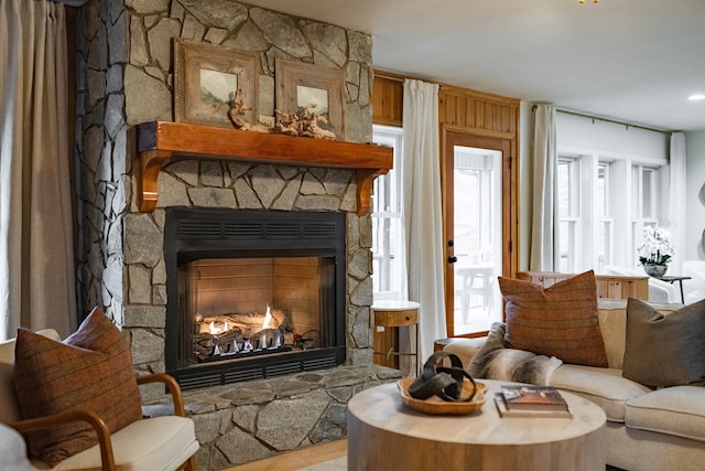 living area featuring plenty of natural light, wood walls, and a stone fireplace