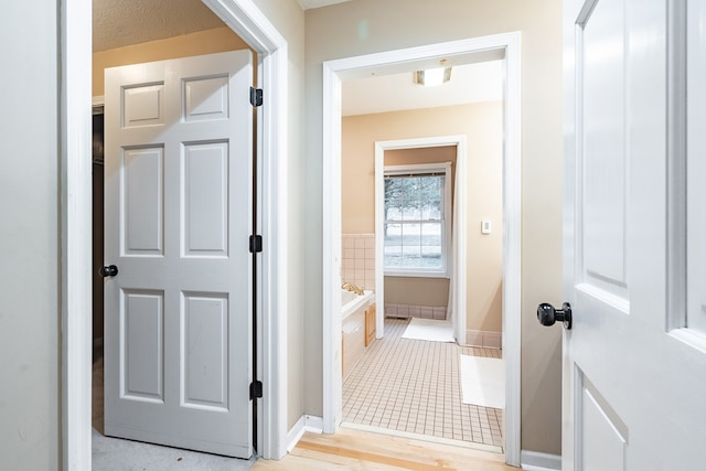 bathroom with a relaxing tiled tub and a textured ceiling